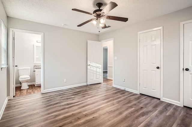 unfurnished bedroom featuring a textured ceiling, dark wood-type flooring, ceiling fan, and ensuite bathroom