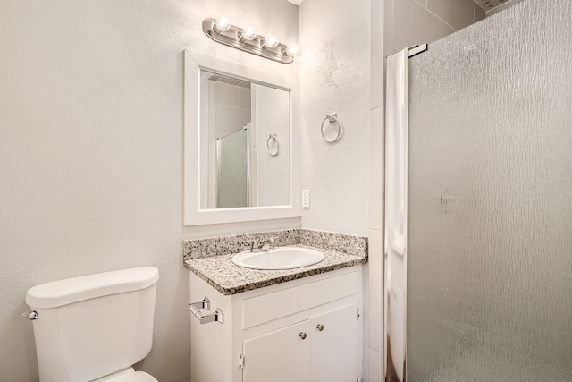 full bathroom with a shower stall, vanity, toilet, and a textured wall