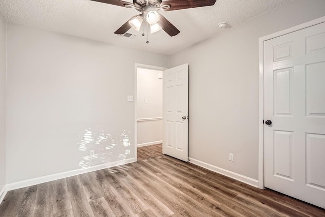unfurnished bedroom featuring visible vents, ceiling fan, baseboards, wood finished floors, and a textured ceiling