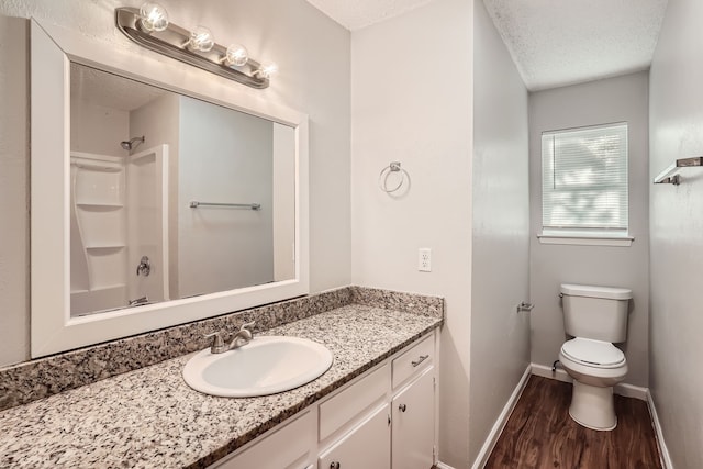 bathroom with wood-type flooring, toilet, vanity, and a textured ceiling