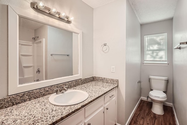 full bath with vanity, wood finished floors, baseboards, a textured ceiling, and toilet