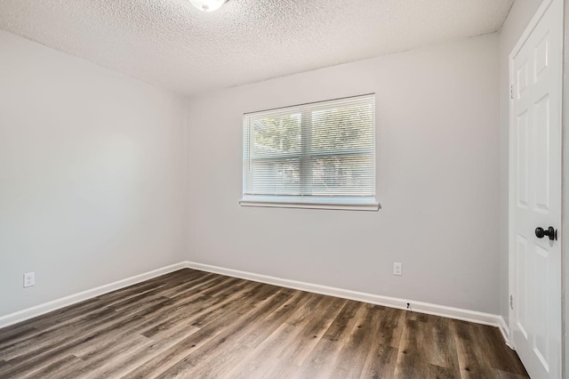 spare room with baseboards, a textured ceiling, and wood finished floors