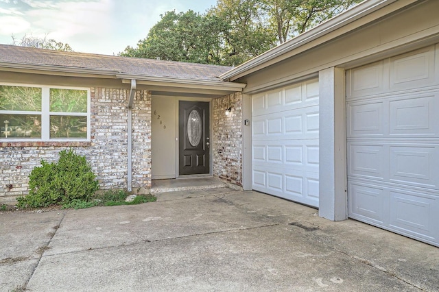 doorway to property with brick siding, driveway, and a garage