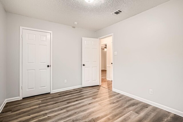 unfurnished bedroom with a closet, dark hardwood / wood-style flooring, and a textured ceiling