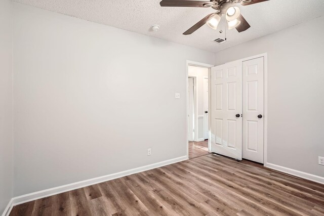 unfurnished bedroom featuring a textured ceiling, hardwood / wood-style floors, ceiling fan, and a closet