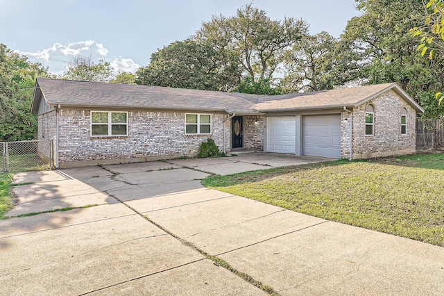 single story home with driveway, fence, a front yard, an attached garage, and brick siding