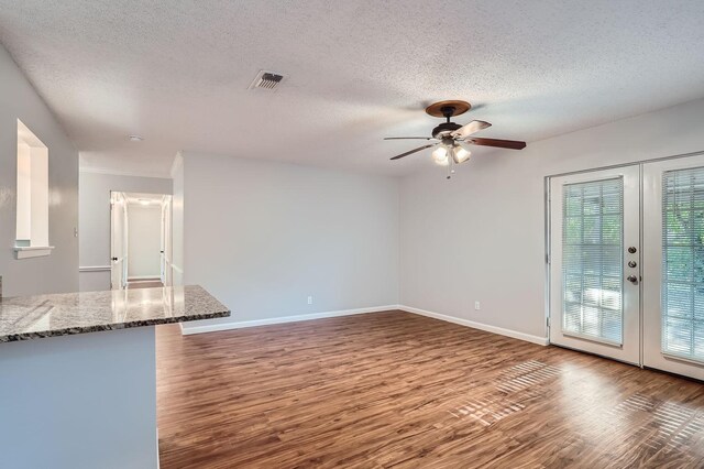 unfurnished living room featuring dark wood-type flooring, ceiling fan, a textured ceiling, and french doors