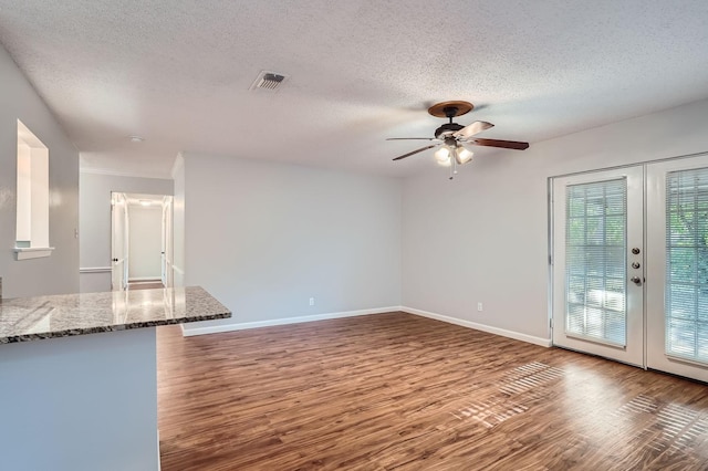 unfurnished living room with wood finished floors, visible vents, french doors, and baseboards