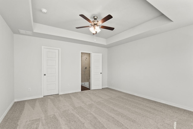 unfurnished bedroom featuring carpet, ceiling fan, and a raised ceiling