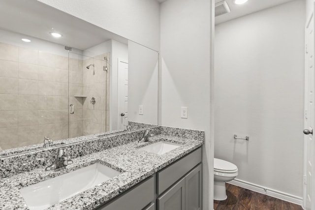 bathroom featuring vanity, hardwood / wood-style flooring, walk in shower, and toilet