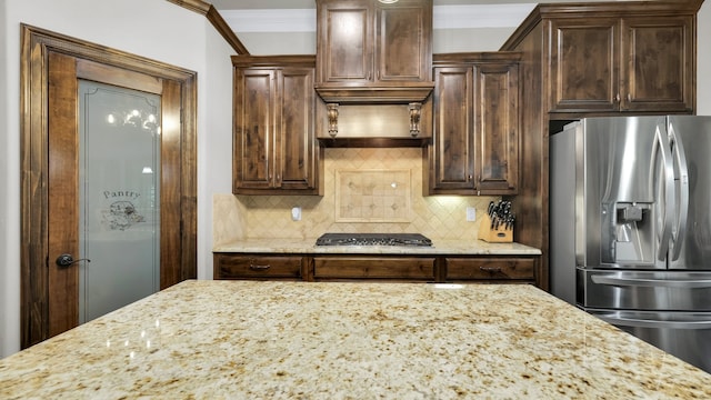 kitchen featuring appliances with stainless steel finishes, light stone countertops, tasteful backsplash, dark brown cabinetry, and ornamental molding