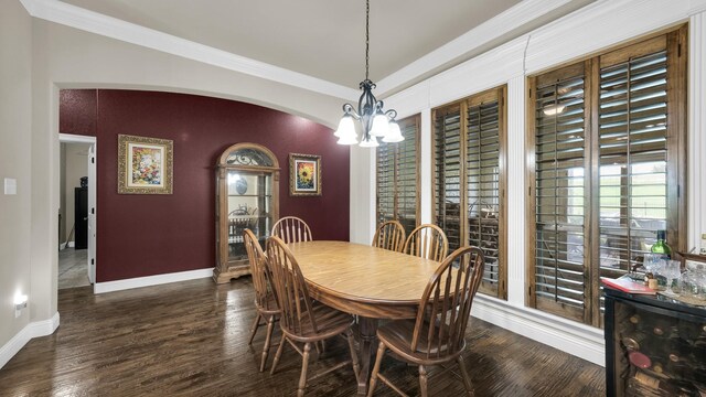 dining space featuring crown molding, dark wood-type flooring, and an inviting chandelier