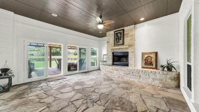 living room with wooden ceiling, ceiling fan, and a stone fireplace