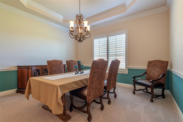 carpeted dining area featuring a chandelier, a tray ceiling, and ornamental molding