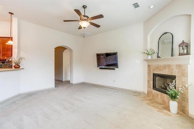 unfurnished living room with a tile fireplace, light carpet, and ceiling fan