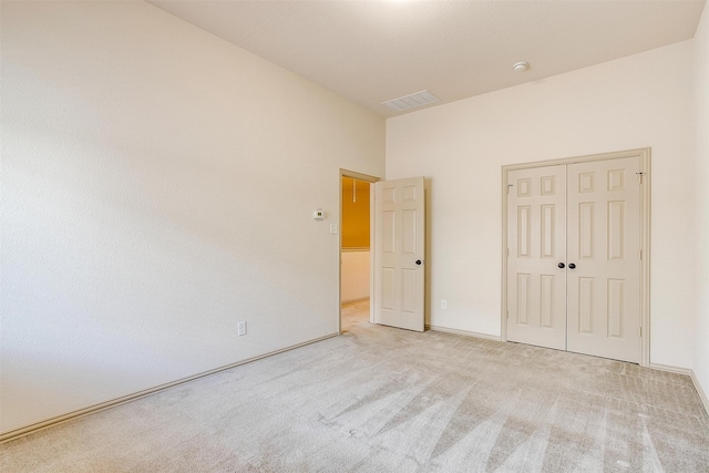 unfurnished bedroom with a closet and light colored carpet