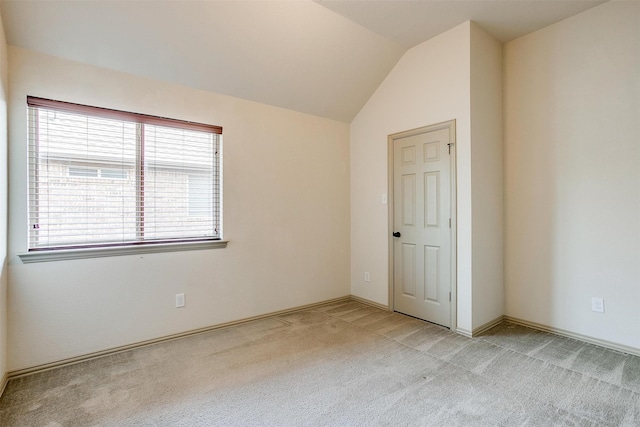 carpeted spare room with vaulted ceiling