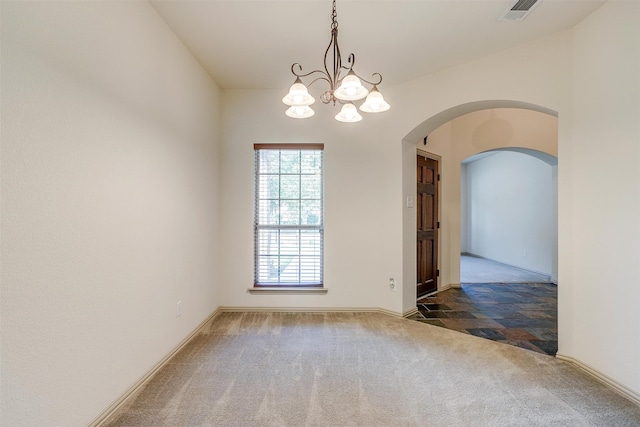 empty room featuring dark colored carpet and a chandelier