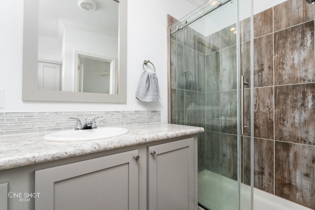 bathroom featuring vanity, ornamental molding, walk in shower, and tasteful backsplash