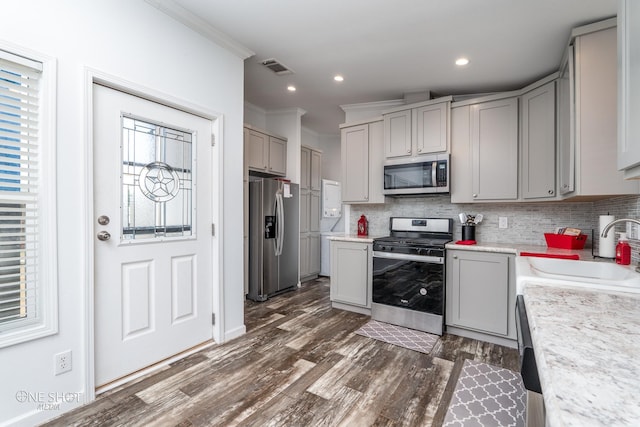 kitchen featuring backsplash, crown molding, stainless steel appliances, sink, and dark wood-type flooring