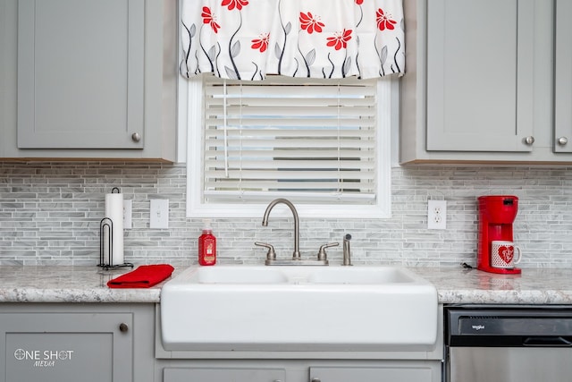 kitchen featuring dishwasher, sink, light stone countertops, and tasteful backsplash