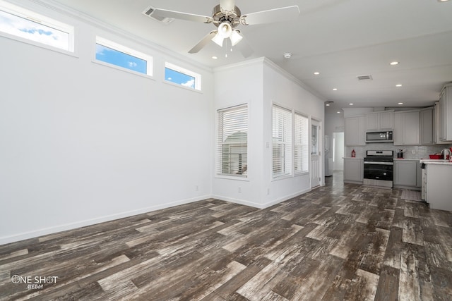 unfurnished living room with crown molding, dark hardwood / wood-style flooring, a towering ceiling, and ceiling fan