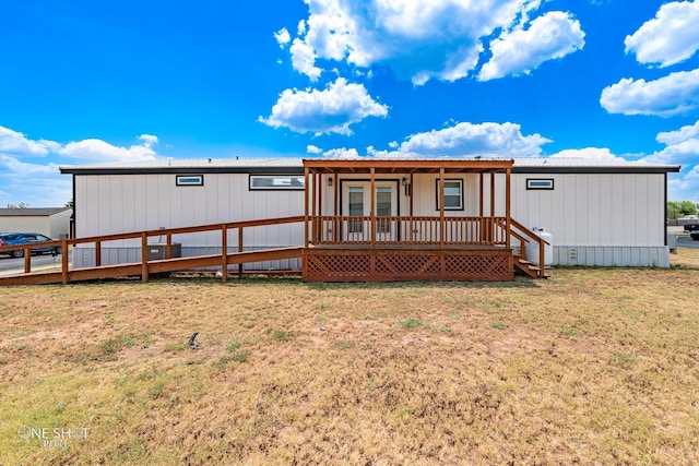 back of property featuring a wooden deck and a lawn