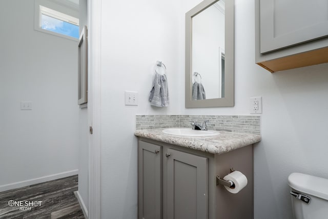 bathroom with backsplash, toilet, hardwood / wood-style flooring, and vanity