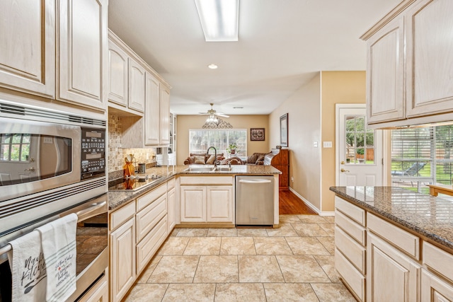 kitchen with ceiling fan, dark stone countertops, stainless steel appliances, and a healthy amount of sunlight