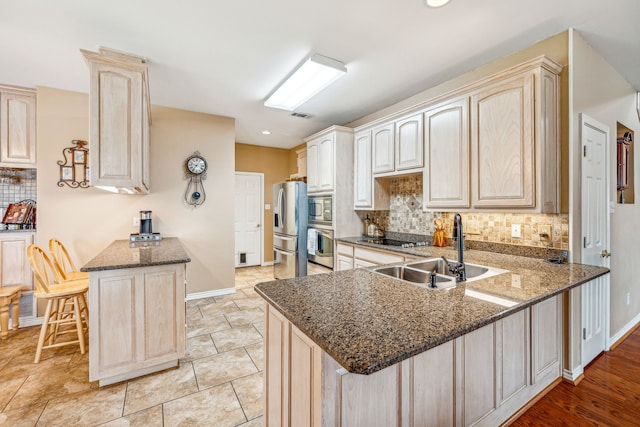 kitchen featuring dark stone countertops, appliances with stainless steel finishes, kitchen peninsula, and sink