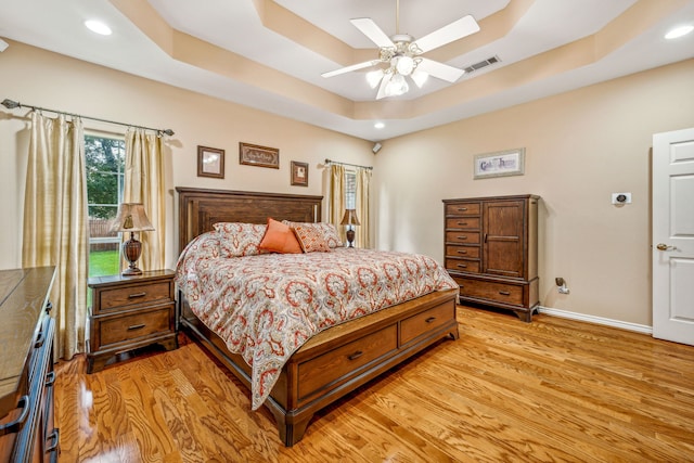 bedroom featuring a tray ceiling, ceiling fan, and light hardwood / wood-style floors