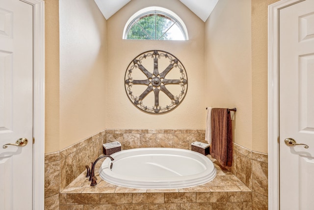 bathroom with lofted ceiling and tiled tub