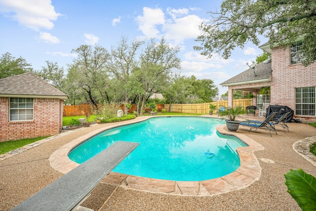 view of swimming pool with a diving board and a patio