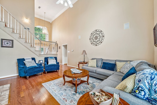 living room featuring crown molding, hardwood / wood-style flooring, a high ceiling, and ceiling fan