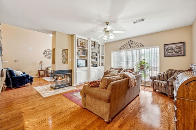 living room with light hardwood / wood-style floors, ceiling fan, and a multi sided fireplace