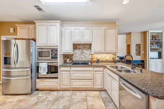 kitchen featuring appliances with stainless steel finishes, sink, dark stone counters, kitchen peninsula, and decorative backsplash