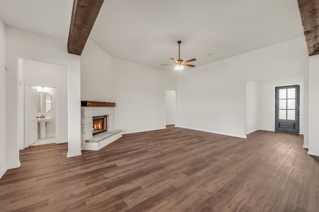 unfurnished living room featuring ceiling fan, beam ceiling, dark hardwood / wood-style flooring, and a fireplace