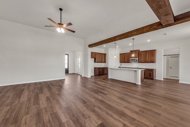 unfurnished living room with dark wood-type flooring, ceiling fan, beamed ceiling, and sink