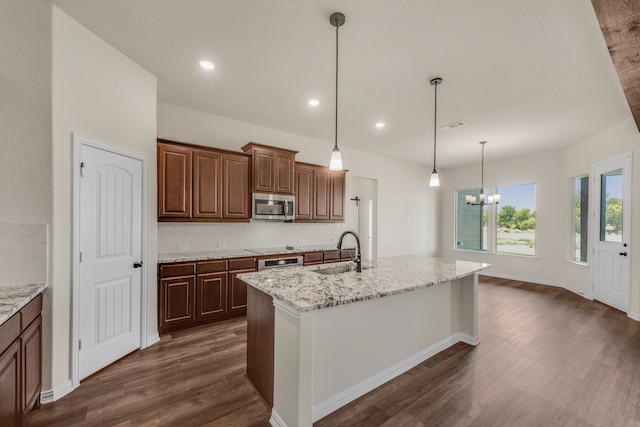 kitchen with an inviting chandelier, stainless steel appliances, dark hardwood / wood-style flooring, sink, and a center island with sink