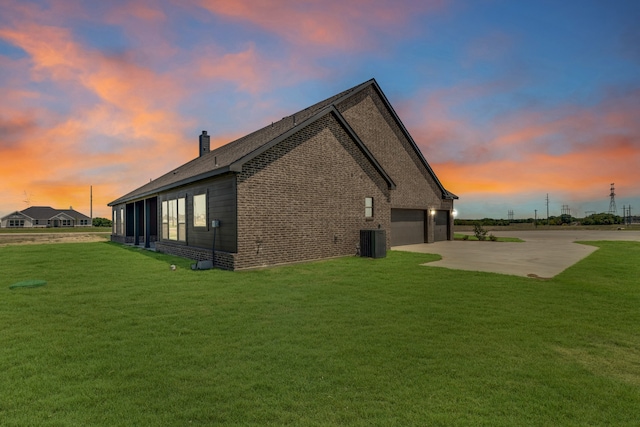 property exterior at dusk featuring a garage, a lawn, and cooling unit