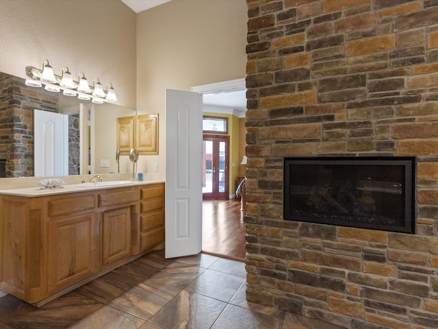 bathroom with french doors, wood-type flooring, vanity, and a stone fireplace