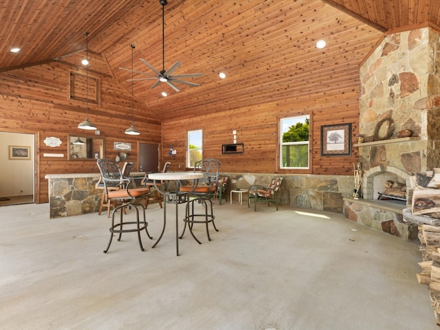 dining area featuring wood ceiling, ceiling fan, a stone fireplace, and high vaulted ceiling