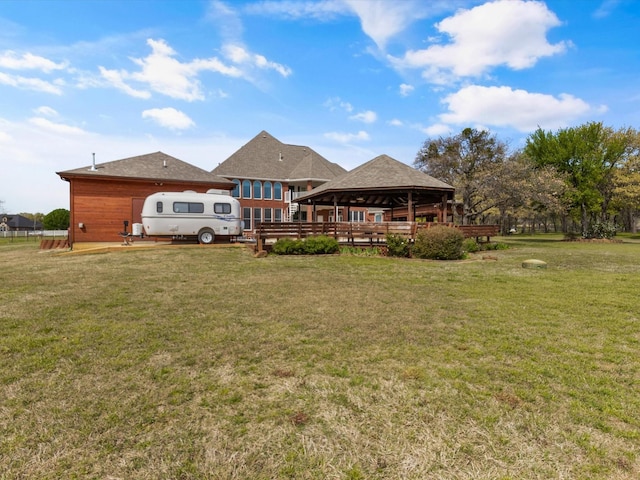 rear view of property featuring a lawn and a gazebo