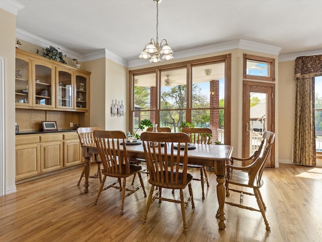 dining space with crown molding, a notable chandelier, a wealth of natural light, and light wood-type flooring