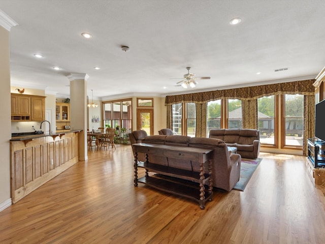 living room with visible vents, light wood-type flooring, recessed lighting, and ornamental molding