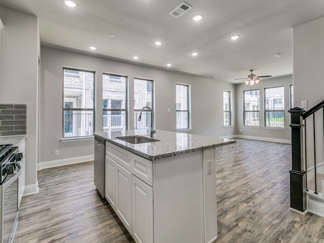 kitchen with light hardwood / wood-style flooring, appliances with stainless steel finishes, sink, ceiling fan, and a center island with sink