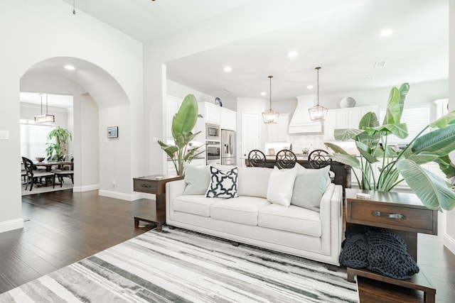 living area featuring baseboards, recessed lighting, arched walkways, and dark wood finished floors