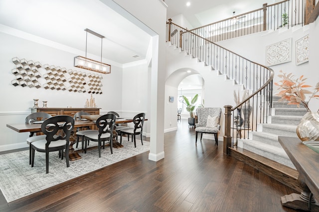 dining area with crown molding, dark wood-type flooring, and a high ceiling