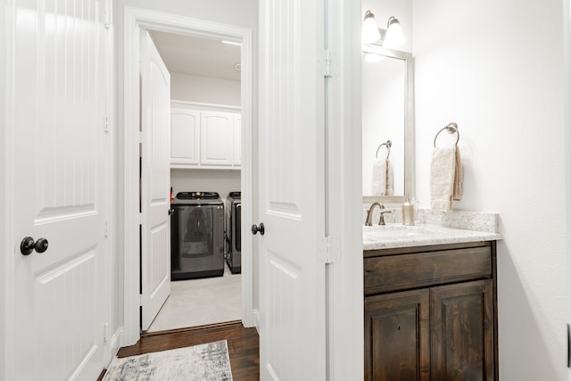 bathroom featuring hardwood / wood-style floors, washing machine and clothes dryer, and vanity