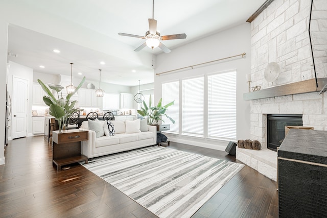 living room with dark wood-type flooring, ceiling fan, a fireplace, and recessed lighting